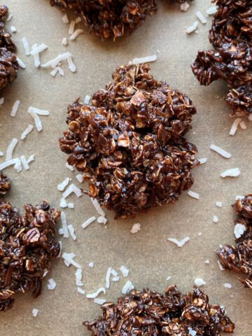 No Bake Cookies with scattered coconut flakes on a piece or parchment paper.