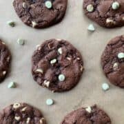 Mint Chocolate Chip Cookies on a piece of parchment paper with mint chocolate chips scattered around the cookies.
