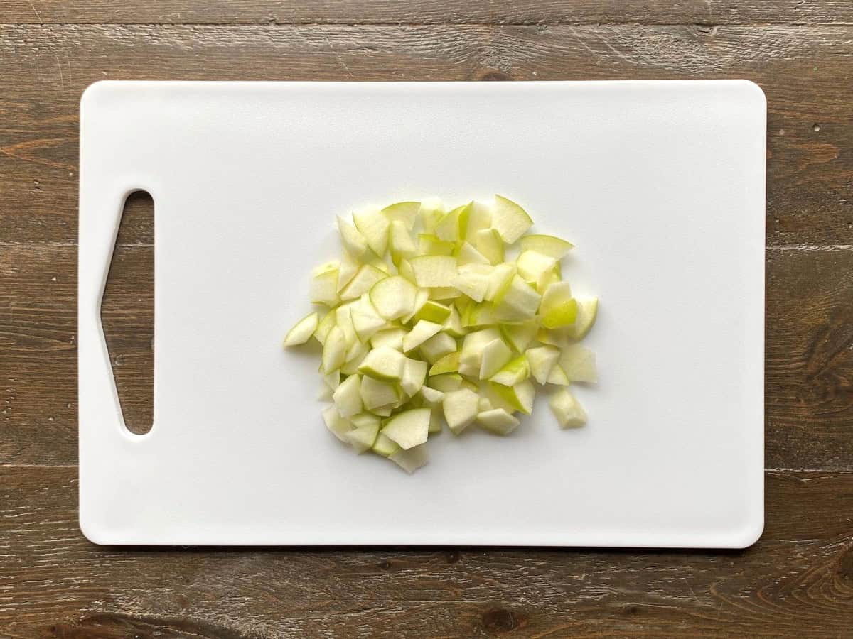 Chopped apples on a white cutting board.