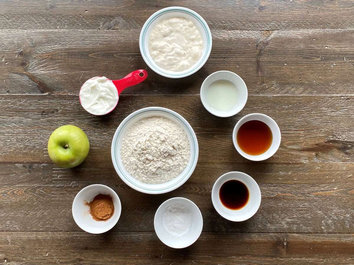 Ingredients for apple scones measured and laid out on a brown wooden surface.