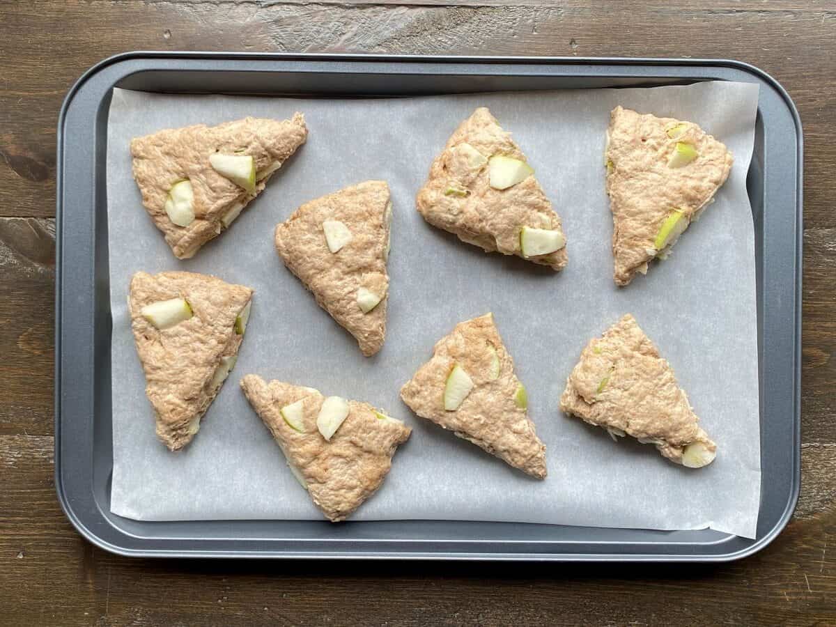 Dough triangles place on a large baking pan lined with parchment paper.
