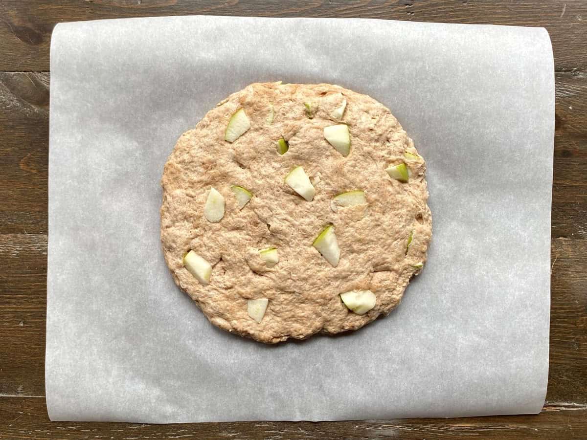 Dough is shaped into a flat round disc on top of white parchment paper.