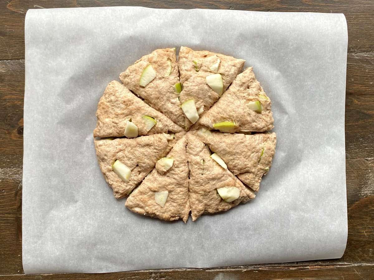 Dough is cut into eight equal triangle shaped pieces on top of white piece of parchment paper.